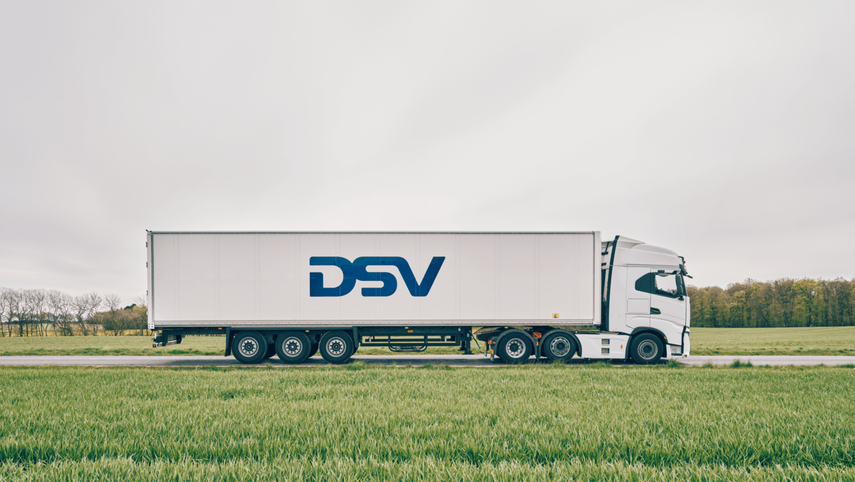 DSV trailer står på vei med gressplen på hver side.